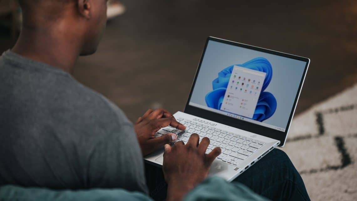 man in gray long sleeve shirt using Windows 11 computer