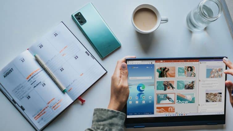 person using Windows 11 computer beside white ceramic mug on white table